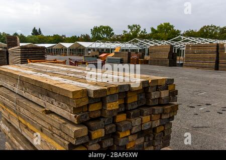 Costruzione di stand di una fiera regionale, costruzione di tende, pali di legno e tavole di legno per il pavimento della tenda sulla pila, tende sullo sfondo, alu Foto Stock