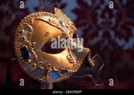 Elegante ed elegante maschera di carnevale dorata su una superficie di velluto rosso Foto Stock