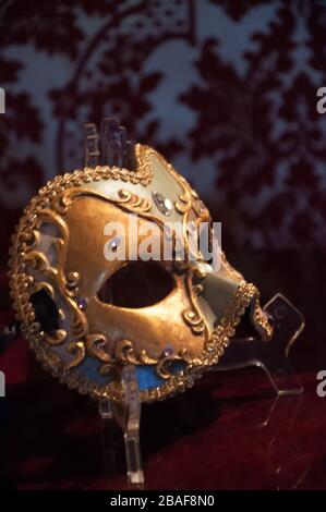 Elegante ed elegante maschera di carnevale dorata su una superficie di velluto rosso Foto Stock