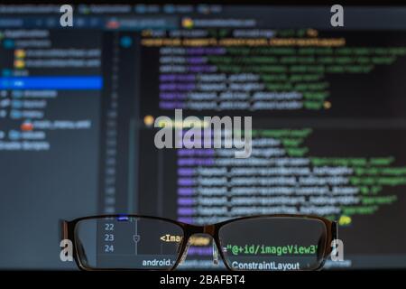 guardando attraverso gli occhiali alla schermata dello sviluppatore con codice php, notebook Foto Stock