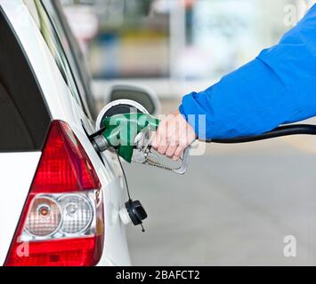 Colpo orizzontale del braccio e della mano della donna che pompano il gas nella sua automobile. Foto Stock