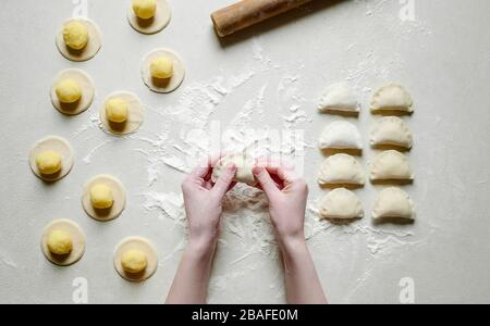 Donna mani sculture gnocchi con patate su sfondo bianco. Cibo ucraino tradizionale. Foto Stock