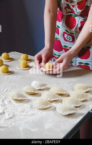 Donna mani sculture gnocchi con patate su sfondo bianco. Cibo ucraino tradizionale. Foto Stock