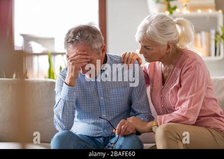 Donna anziana che consola suo marito a casa Foto Stock