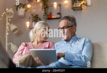 Coppia matura utilizzando un computer portatile mentre si rilassa a casa Foto Stock