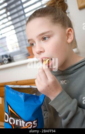 Ragazza giovane che mangia Doritos Foto Stock