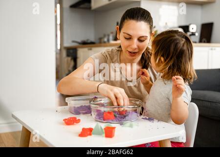 Madre giovane con bambino che gioca sabbia cinetica. Buon tempo di Unione insieme. Sviluppo della creatività Foto Stock