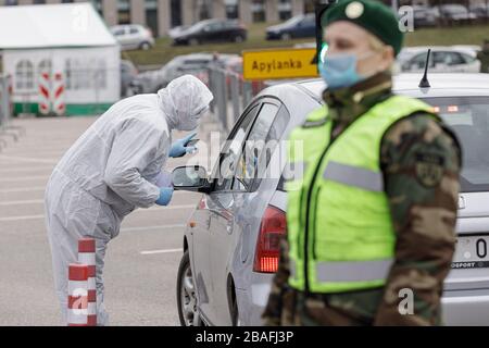 Vilnius, Lituania, 19 marzo 2020. Il personale medico in dispositivi di protezione raccoglie i campioni per il coronavirus COVID-19 presso il centro di test mobile Drive-in o Foto Stock