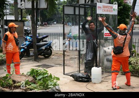 I residenti che saranno attivi in luoghi pubblici, utilizzano la camera di disinfezione di Blok M, South Jakarta, Indonesia il 25 marzo 2020. In questa camera di sterilizzazione tutto il corpo della persona verrà spruzzato con liquido disinfettante. Questo liquido disinfettante ha la funzione di uccidere il virus della corona che si attacca ai vestiti o al corpo della persona, per anticipare la diffusione del virus della corona (COVID-19) negli spazi pubblici. (Foto di Kuncoro Widyo Rumpoko/Pacific Press/Sipa USA) Foto Stock