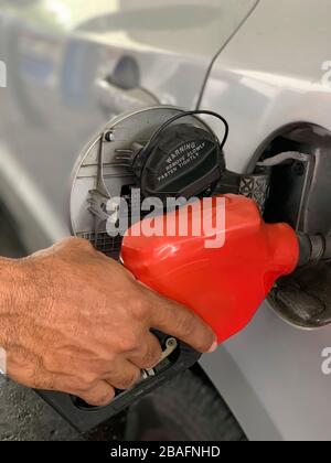 Mano di un uomo con una manichetta di carburante che fa rifornimento di un veicolo con pompa e tubo self-service, Panama, America Centrale Foto Stock