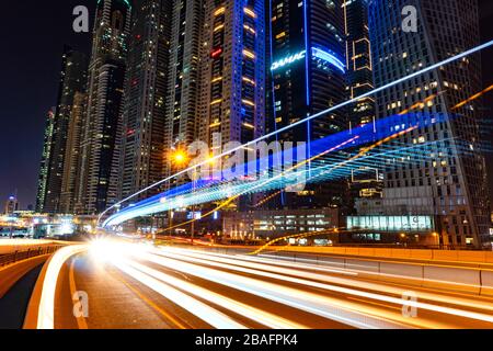 Vista panoramica del quartiere illuminato di Dubai Marina nella città di Dubai di notte con lunghe tracce di auto leggere a esposizione, Emirati Arabi Uniti. Foto Stock