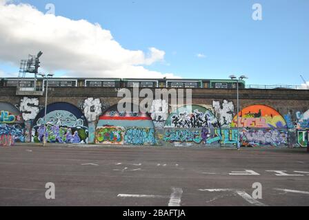 ARCHI FERROVIARI DI PECKHAM COPERTI DI GRAFFITI CON UN TRENO FERROVIARIO MERIDIONALE CHE PASSA SOPRA. Foto Stock