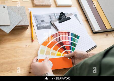 Mani di giovane designer femminile di interni che tengono tavolozza colori sulla scrivania, mentre la scelta adatto per il nuovo ordine del cliente Foto Stock