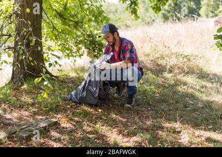 Giovane uomo che raccoglie cucciolata nel suo parco locale Foto Stock