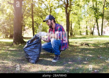 Giovane uomo che raccoglie cucciolata nel suo parco locale Foto Stock