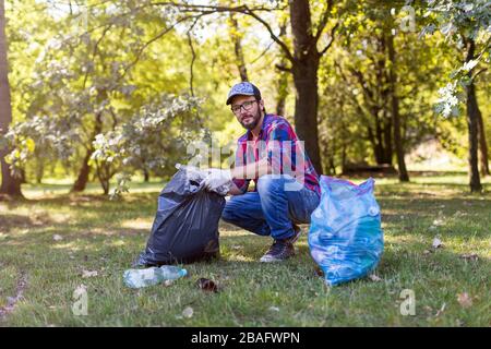 Giovane uomo che raccoglie cucciolata nel suo parco locale Foto Stock