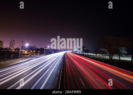 Lunga esposizione dei fasci di luce bianca e rossa delle auto da traffico mentre si muove lungo l'autostrada della città Foto Stock