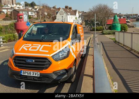 Leigh-on-Sea, Regno Unito. 27 marzo 2020. Un furgone di pattuglia RAC (Royal Automobile Club) parcheggiato vicino al lungomare di Leigh-on-Sea, Essex, durante il blocco COVID-19. La scena evidenzia i servizi di assistenza stradale a sostegno dei keyworker e dei viaggi essenziali durante la pandemia. Boe marittime e architettura costiera incorniciano il furgone, simboleggiando la resilienza e il servizio pubblico in un periodo di movimento limitato. Penelope Barritt/Alamy Live News Foto Stock