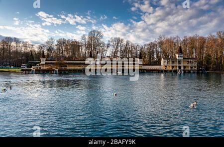 HEVIZ, UNGHERIA - 7 MARZO: La gente nuota nel lago termale di fronte alla casa da bagno il 7 marzo 2020 a Heviz, Ungheria. Foto Stock