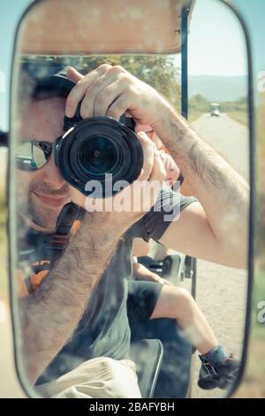 L'uomo israeliano ha riflesso sullo specchio laterale di un golf cart elettrico mentre scattava un'immagine di autoritratto. Viaggia nella campagna di Israeliano Hul Foto Stock