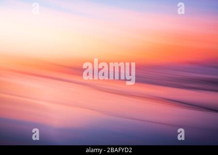 Movimento Blur delle belle tonalità di rosso, viola e arancio tramonto colore sopra l'acqua di un lago Foto Stock