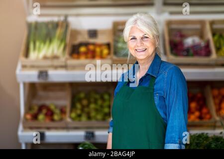 Donna senior che lavora in un piccolo negozio di alimentari Foto Stock