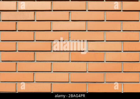 La struttura del muro di una nuova casa di mattoni rossi illuminata dal sole. Sfondo Foto Stock