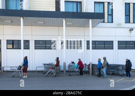 Newquay, Cornovaglia, Regno Unito. 27 marzo 2020. Gli acquirenti che fanno la fila pazientemente fuori di un supermercato e osservano le distanze sociali consigliate dal governo a causa della pandemia di Coronavirus. Gordon Scammell/Alamy Live News. Foto Stock