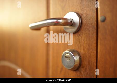 Porta in legno marrone lucido con maniglia cromata e serratura, vista laterale primo piano Foto Stock