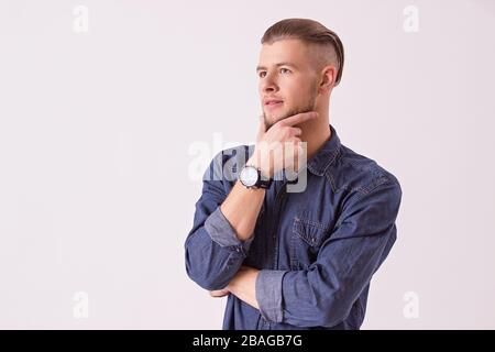 L'ippopotamo con barba tocca il mento con la mano e guarda lontano mentre si leva in piedi su sfondo bianco. Giovane uomo attraente pensare mentre isolato sul retro Foto Stock