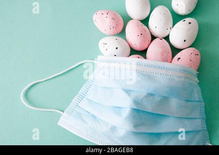 Concetto di quarantena di Pasqua. Maschera di protezione , uova colorate, assistenza sanitaria. Foto Stock