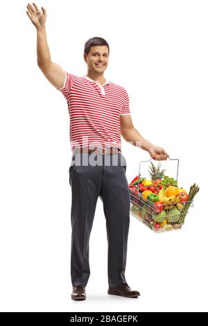 Ritratto a tutta lunghezza di un giovane che agita e tiene un cestino con frutta e verdura isolate su sfondo bianco Foto Stock