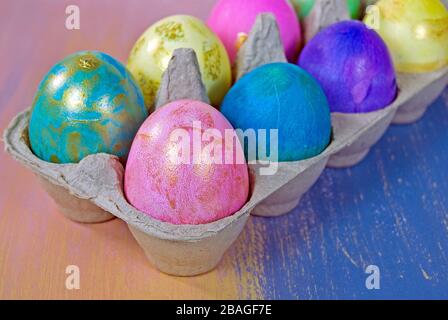 Primo piano di colorate uova di Pasqua con accento dorato in cartone grigio Foto Stock