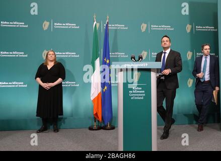 Taoiseach Leo Varadkar (centro) e Ministro della Sanità Simon Harris arrivano agli edifici governativi per un briefing stampa sui coronavirus, dove hanno annunciato a partire dalla mezzanotte di questa sera e per un periodo di due settimane, tutti in Irlanda devono rimanere a casa, salvo circostanze specifiche. Foto Stock