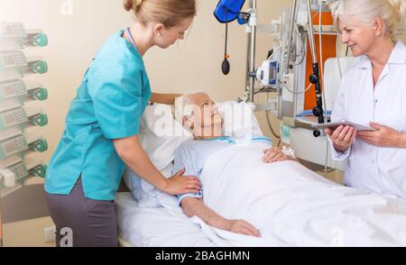 Paziente anziano con medico e infermiere in ospedale Foto Stock