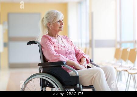 Donna anziana seduta in sedia a rotelle in ospedale Foto Stock