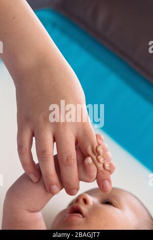 Tiny Newborn Fingers tenendo le mani amorevoli della mamma Foto Stock