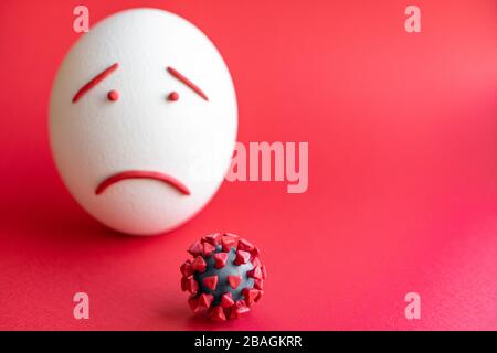 Modello di coronavirus plastificato e isolato di uovo su sfondo rosso. Modello plastilina di coronavirus e uovo di pasqua raffigurante paura e tristezza. Grande Foto Stock