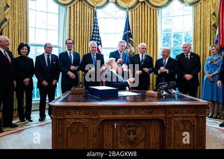 Il presidente degli Stati Uniti Donald J. Trump mette una penna al leader della minoranza della Camera degli Stati Uniti Kevin McCarthy (repubblicano della California) dopo aver firmato il progetto di legge sui coronavirus da due trilioni di dollari nell’Ufficio ovale alla Casa Bianca di Washington, DC il 27 marzo 2020. PROM da sinistra a destra: Il segretario AMERICANO dell'agricoltura Sonny Perdue; il segretario americano dei trasporti Elaine Chao; il direttore del Consiglio economico nazionale Larry Kudlow; il segretario americano del Tesoro Steven T. Mnuchin; il leader maggioritario del Senato americano Mitch McConnell (repubblicano del Kentucky); il capo McCarthy; il vicepresidente americano Mike Pence; i rappresentanti degli Stati Uniti Foto Stock
