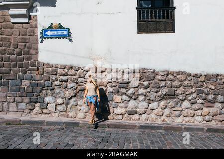 Una giovane donna sta in piedi vicino ad un muro bianco a Cusco, Perù Foto Stock