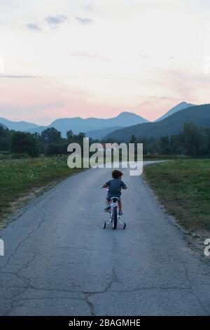 Little Boy Riding una bicicletta in montagna Foto Stock