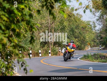 Uomo anziano che guida la sua moto avventura su strade tortuose nel Nord della Thailandia Foto Stock