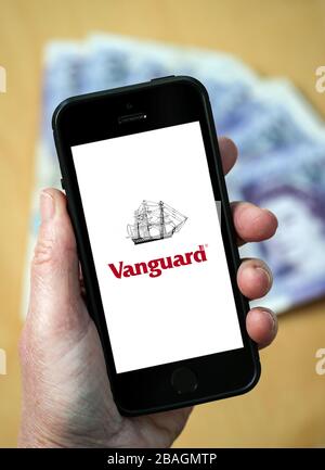 Una donna che guarda il logo Vanguard fund management Company su un telefono cellulare. (Solo per uso editoriale) Foto Stock