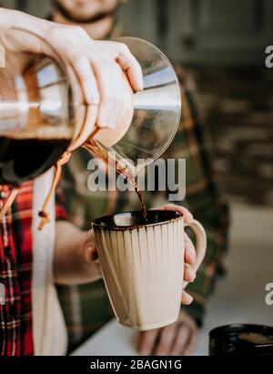 il caffè caldo viene versato da un versare in una tazza di caffè abbronzata Foto Stock