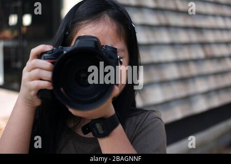 Primo piano: Guarda una ragazza scatta una foto con una fotocamera DSLR grande Foto Stock