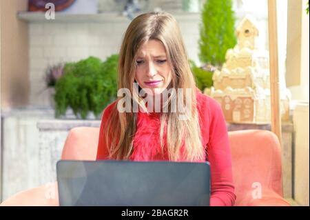 donna sconvolta che lavora a casa con un computer portatile Foto Stock