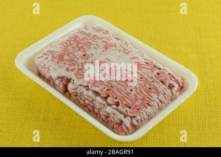 Carne di hamburger cruda congelata in confezioni di macellaio di polistirene sul tavolo Foto Stock