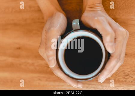 Tazza di caffè nero estratto sul tavolo di legno. Foto Stock