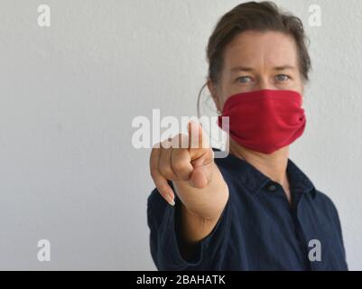 La donna caucasica si pone per la macchina fotografica con la sua maschera facciale fai da te (fatta da una vecchia maglietta manica) durante l'epidemia di corona-virus 2019/20. Foto Stock