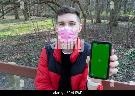 Uomo in maschera medica tenere cellulare con verde schermo vuoto. Epidemia nuova diffusione rapida coronavirus 2019-ncov medicina influenza virus concetto Foto Stock